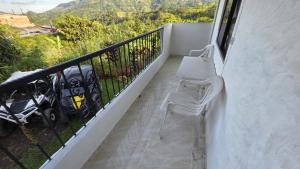 a balcony with two white chairs and a table at CASA HOTEL COCORNa in Cocorná +9 photos