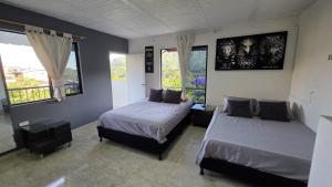 a bedroom with two beds and two windows at CASA HOTEL COCORNa in Cocorná