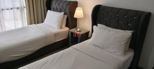 a bedroom with two beds with white sheets and a lamp at Imperial resident time Square KL in Kuala Lumpur +33 photos