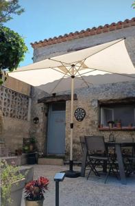 a table with an umbrella in front of a building at Le refuge de Teddy in Solliès-Toucas
