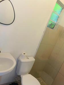 a white bathroom with a toilet and a sink at Pousada Coral in Osório
