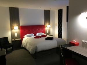 - une chambre avec un grand lit et une tête de lit rouge dans l'établissement Le Beverl'inn, à Flers