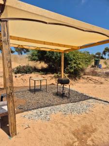 a yellow umbrella with a table and a stool under it at Los Olivos del Colibri in Tambillos