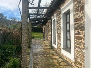 a walkway outside of a brick building with a pergola at Casa Benaxo Ribeira Sacra in Currelos