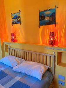 a bedroom with orange walls and a bed with two lamps at Sala dell Estate Guest House in Secchia