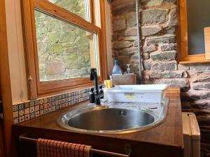 a sink in a kitchen with a stone wall at Oakdean Cottage Yurt in Blakeney +41 photos