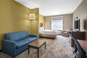 a hotel room with a bed and a blue couch at Best Western Plus Chalmette Hotel in Chalmette