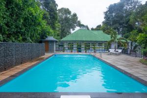 a large blue swimming pool in front of a building at Misty Lake Resorts Munnar By Sylora Hotels in Munnar