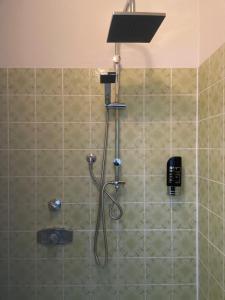 a shower with a shower head and a phone on the wall at Pension und Restaurant La Casa in Undeloh