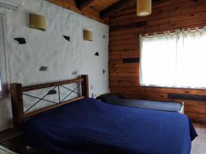 a bedroom with a blue bed and a window at Posada La Solana in El Cadillal