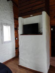 a room with a white wall with a flat screen tv at Posada La Solana in El Cadillal