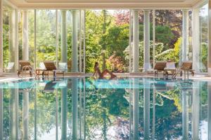 a pool in a house with chairs and a person sitting in the water at Brenners Park Hotel & Spa, Oetker Hotels in Baden-Baden