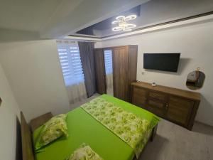 a bedroom with a green bed and a television at Apartament Eduard in Techirghiol