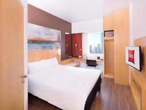 a hotel room with a large white bed and a desk at ibis Dubai One Central in Dubai +164 photos