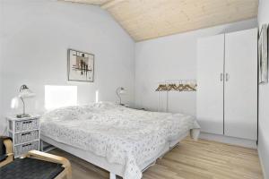 a white bedroom with a bed and a chair at LN1094-Hirtshals-Strandklitten-2 in Hirtshals