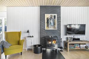a living room with a fireplace and a yellow chair at LN1094-Hirtshals-Strandklitten-2 in Hirtshals