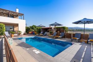 a swimming pool with chairs and umbrellas on a house at Villa Sandy Evi by Villa Select in Astérion