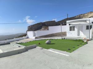 a building with a grassy yard in front of a house at Kampanelia Village Suites in Fira