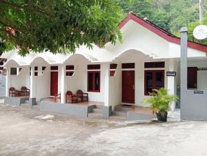 a white house with red doors and a tree at Sarwi Endah Beach Cottage in Tepus +9 photos