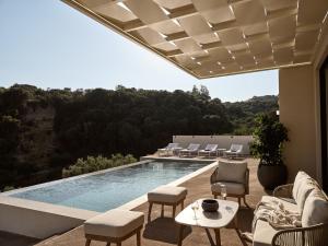 a swimming pool with chairs and a table on a patio at Villa Theta by Villa Select in Kalamaki