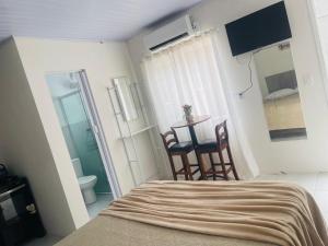 a bedroom with a bed and a table and chairs at Pousada Coral in Osório