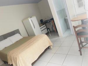 a bedroom with a bed and a table and a chair at Pousada Coral in Osório