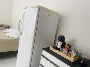 a white refrigerator in a room with a bed at Pousada Coral in Osório