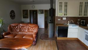 a living room with a leather couch and a kitchen at Domek v údolí in Božanov