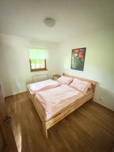 a bedroom with a bed with white sheets and pink pillows at Domek v údolí in Božanov