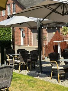 a group of chairs and tables under an umbrella at Pension und Restaurant La Casa in Undeloh