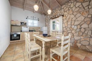 a kitchen with a table and chairs and a stone wall at Villa Helona in Keri