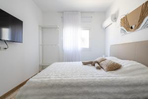 a white bedroom with a bed with a stuffed animal on it at Villa 65 in Ilaniyya +6 photos