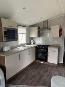 a kitchen with white cabinets and a sink and a stove at Sea Breeze Lodge in Longniddry +10 photos