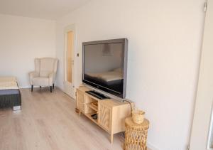 a living room with a flat screen tv and a chair at Korbzimmer Apartment in Lichtenfels