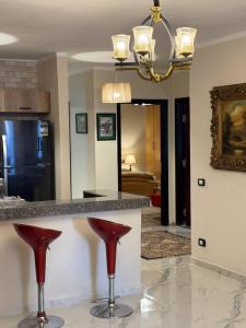 a kitchen with a counter with two red bar stools at Compound Canarya - 3 Bedroom Apartment in 6th Of October