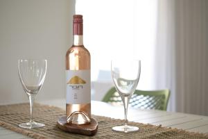 a bottle of wine sitting on a table with two glasses at Villa 65 in Ilaniyya
