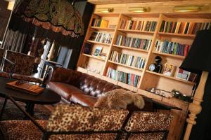a living room with a brown leather couch and book shelves at 1740 Boutique Hotel Kazbegi in Kazbegi