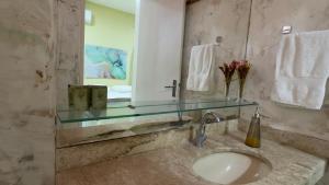 a bathroom with a sink and a mirror and towels at Pousada Holy Salt Cumbuco in Caucaia