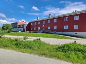 a large red building with a road in front of it at Porsangerfjorden Lodge in Børselv