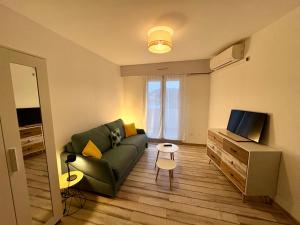 a living room with a green couch and a television at Lovely studio with balcony - central location in Cavalaire-sur-Mer