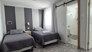 a bedroom with two beds and a bathroom with a toilet at Colores Rio Cuarto in Río Cuarto
