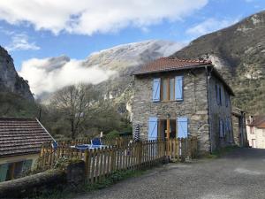 a stone house with a fence in front of a mountain at Gite Julie Anne in Ussat