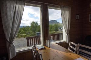 a dining room with a table and a large window at Ailakka, huoneisto A in Kilpisjärvi