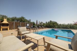 a swimming pool with chairs and a table next to it at Villa Helona in Keri