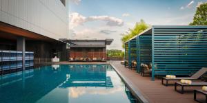 a swimming pool with chairs and a building at voco Kuching by IHG in Kuching