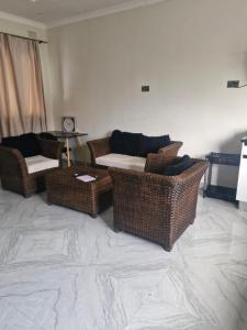 a living room with three wicker chairs and a couch at Cosy Corner Villa in Lusaka