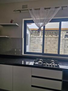 a kitchen with a stove top oven next to a window at Cosy Corner Villa in Lusaka