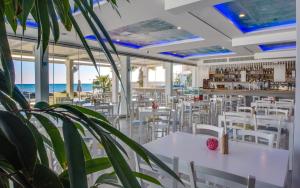 a restaurant with white tables and chairs and the ocean at Island Boutique Hotel in Larnaca