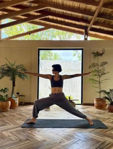 a woman doing a yoga pose in a room at Casa del Pavo Real Boutique Hotel Yoga & Spa in Palomino