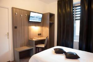 a room with a bed and a desk and a television at Le Beverl'inn in Flers +39 photos